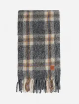 Bufanda gris con diseño de cuadros escoceses en tonos beige, marrón y azul. Tiene flecos en los extremos y una etiqueta de cuero con el logo de la marca.