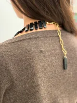 Collar corto de obsidiana natural con piezas rectangulares negras, cadena de extensión dorada y dije colgante de piedra.
