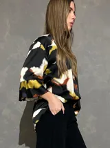 Blusa de manga larga acampanada con estampado abstracto en tonos negro, blanco, verde lima y caramelo, de corte holgado.