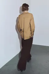 Camisa de corte amplio confeccionada en algodón, con cuello solapa, manga larga con puños y cierre frontal con botones ocultos bajo solapa. Presenta un bolsillo frontal en el pecho.