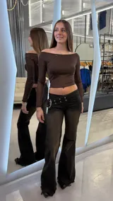 Pantalón de jean tiro bajo con efecto lavado desgastado en color negro. Presenta un diseño de pierna ancha con ruedo desflecado y una cintura con detalle de cinturón integrado con hebilla metálica grande y ojales.