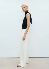 Jeans wide leg de tiro medio color blanco marfil, con diseño largo, trabillas para cinturón, cierre de botón y cremallera, cuatro bolsillos y detalle de pinzas delanteras.
