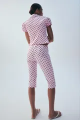 Chaqueta corta rosa con estampado de lunares negros, de cuello solapa y manga corta abullonada. Cuenta con falsos bolsillos con solapa en el delantero y cierre frontal con botones.