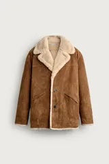 Campera marrón de piel con interior de borreguillo color crudo, de corte regular fit, con cuello bowling, bolsillos de doble vivo y cierre frontal con botones.