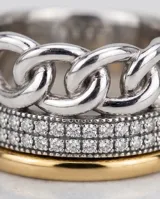 Anillo ancho de plata 925 y lámina de oro 18k, con diseño de eslabones de cadena en la parte superior, una franja central con incrustaciones de circonias y base dorada.