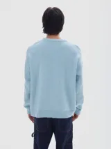 Buzo de punto color celeste, con cuello redondo y manga larga, de calce holgado y puños acanalados.