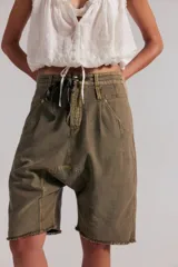 Short de algodón texturado color verde militar, de largo hasta la rodilla y tiro caído estilo harem, con cintura elastizada ajustable mediante cordón, cuatro bolsillos y terminación de ruedo deshilachado.