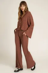 Pantalón de tiro alto confeccionado en tejido de punto acanalado ancho, con pierna sutilmente ancha, cintura elástica y bolsillos laterales.