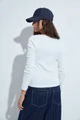 Remera de manga larga con escote cruzado en V, confeccionada en tejido elástico entallado al cuerpo.