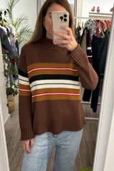Sweater de punto color marrón con cuello alto y diseño de franjas horizontales en tonos mostaza, blanco, negro y rojo en el pecho.