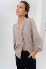 Camisa de manga larga color beige con diseño a rayas sutiles, cuello mao con volados y abertura frontal con detalles de volados a un lado.