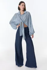 Blusa negra con escote en V, mangas largas abullonadas y lazo para atar en la parte delantera.