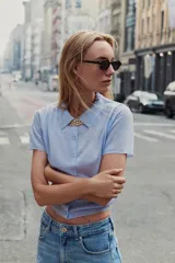 Chaqueta de punto celeste, de manga corta, con cuello solapa y cierre frontal con botones.