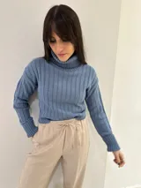 Sweater de punto color verde oliva, con cuello alto y mangas largas con puños acanalados.