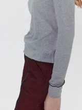 Polera de manga larga confeccionada en tela rib color bordó, con cuello alto y hombreras. Presenta costuras a la vista con pespuntes en hilo de color contrastante en el cuello, puños, hombros y ruedo.