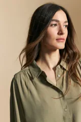 Camisa de manga larga color celeste, con cuello clásico, cierre frontal con botones y puños elastizados con volados. Presenta un diseño fluido con detalle de vainilla en la espalda.