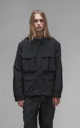Chaqueta técnica liviana de microfibra con acabado mate, diseño con mangas desmontables que permiten convertirla en chaleco. Cuenta con cuello tipo camisa, cierre frontal oculto, cuatro bolsillos frontales de gran tamaño y puños elásticos. Incluye logo bordado en relieve en el pecho.