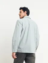 Sobrecamisa verde de manga larga con cuello camisero, cierre frontal con botones y bolsillo de parche en el pecho.