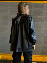 Campera negra con capucha, cierre frontal con cremallera dorada, bolsillos laterales y puños elásticos.