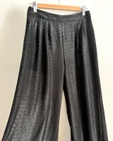 Pantalones negros de pierna ancha con diseño geométrico en lúrex plateado. Tiro medio con detalle de tableados en el frente.
