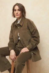 Sobrecamisa de pana color beige, con cuello camisero, cierre frontal con botones metálicos, mangas largas con puños abotonados y lazo ajustable en la cintura.