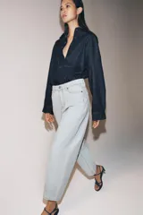 Jeans de tiro alto y silueta tapered, confeccionados en denim negro con costuras en tono contrastante. Cuenta con diseño de cinco bolsillos, trabillas para cinto y cierre frontal con cremallera y botón metálico.