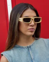 Lentes de sol rectangulares con montura gruesa color beige y cristales negros.