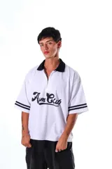 Chomba blanca de pique con cuello y solapa negros, cierre frontal parcial y mangas cortas con ribetes negros. Estampado frontal en cursiva negra.