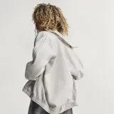 Campera de jean con diseño inspirado en el modelo Firebird de Adidas Originals. Presenta cuello alto, cierre frontal completo, bolsillos laterales y las icónicas tres tiras en las mangas. Posee puños y ruedo elásticos, con el logo del trébol bordado en el pecho.