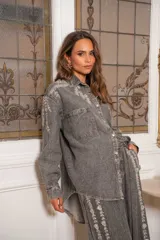 Camisa de jean gris oscuro con botones frontales, bolsillos en el pecho y detalles de brillos plateados en forma de hojas en la parte delantera y mangas.