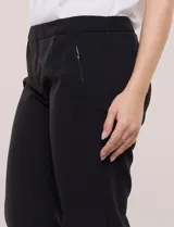 Pantalón de corte cigarette negro, de tiro medio-alto, con pierna sutilmente entallada y bolsillos delanteros con detalle de cierre metálico.