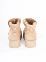 Bota corta tipo ugg con plataforma dentada, confeccionada en material gamuzado color beige con interior forrado en piel sintética.