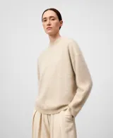 Jersey de mujer color crema, tejido de punto cardado con hombros caídos y cuello perkins.