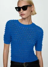 Buzo de punto fino color azul, con diseño entallado, cuello redondo y mangas cortas. Presenta un tejido con textura en relieve.