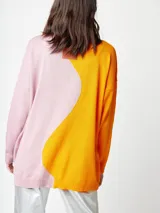 Cárdigan de punto fino bicolor, con un lado amarillo y otro rosado. Tiene bolsillos delanteros y cierre con botones de madera.