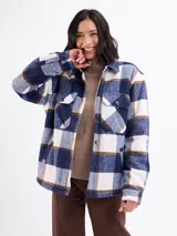 Sobrecamisa de corte holgado con estampado de cuadros en tonos azul, blanco y marrón. Presenta cierre frontal con botones, cuello clásico, bolsillos en el pecho y un interior forrado en sherpa color beige.