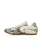 Sneakers Hush Puppies modelo Storm con estampado de piel de serpiente en tonos beige y negro, con detalles de ribetes en color verde oscuro y suela de goma marrón.
