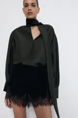 Bermuda de tiro alto de terciopelo negro, con cintura elástica y detalle de encaje tono sobre tono en el ruedo.