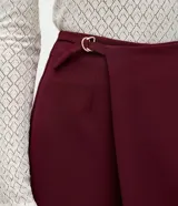 Short pollera de sastrería color bordó, de talle alto y confeccionado en crepé, con diseño estructurado y frente cruzado.