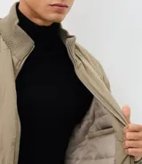 Campera bomber masculina de poliamida, con cuello, puños y ruedo de tejido elástico. Presenta cierre frontal con cremallera, dos bolsillos laterales con solapa y botón, y un pequeño bolsillo con cierre en una de las mangas.