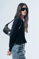 Cardigan negro de punto fino, con cuello redondo, cierre frontal de botones y mangas largas con puños ajustados.