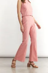 Pantalón de lino color rosado, tiro alto, con corte flare y costura central marcada en el frente de ambas piernas.
