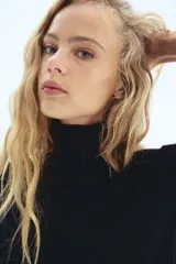 Top de punto fino negro, de manga corta y cuello alto acanalado. Presenta puños y bajo en punto acanalado.