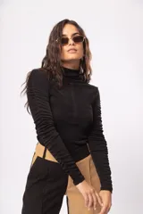 Polera negra de manga larga con cuello alto y detalle de drapeado en las mangas. Confeccionada en tela stretch suave con leve brillo.
