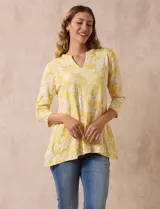 Blusa amarilla estampada con motivos florales en blanco, escote en V y mangas tres cuartos.