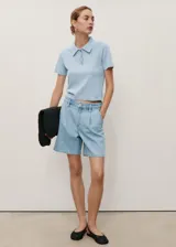Short de denim estilo vaquero, color celeste, de tiro medio con diseño recto, pinzas en el frente y trabillas para cinturón. Cuenta con dos bolsillos laterales y dos bolsillos en la parte posterior.