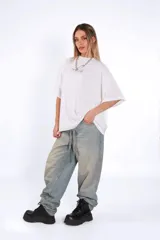 Remera de algodón blanca, corte oversize, con cuello redondo y manga corta. Presenta un pequeño estampado centrado en el pecho con texto en cursiva.