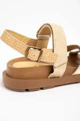 Sandalias planas de cuero en color camel y dorado, con suela track marrón y tiras cruzadas en la parte delantera. Cuentan con tira ajustable en el talón con hebilla metálica.