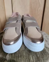 Zapatillas urbanas de cuero color beige y gris metalizado con cierre de doble velcro, detalle animal print en el talón y suela chunky blanca.