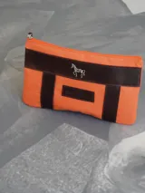 Sobre tipo cartuchera de lona con estampado de camuflaje y terminaciones en cuero marrón.